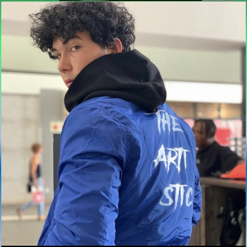 Blue windbreaker, painted THE ARTISTIC stack on the back.