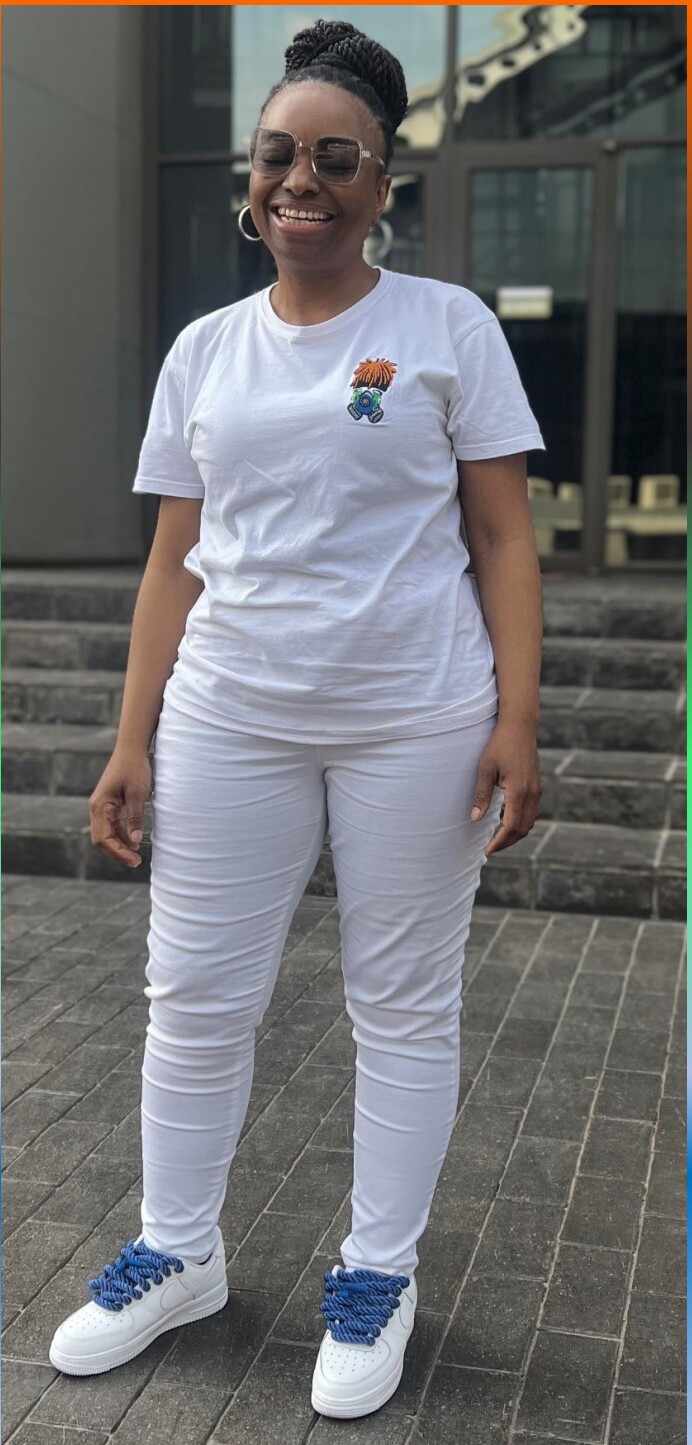 Woman in a clean white tee with embroidered mascot, white pants, blue laces.